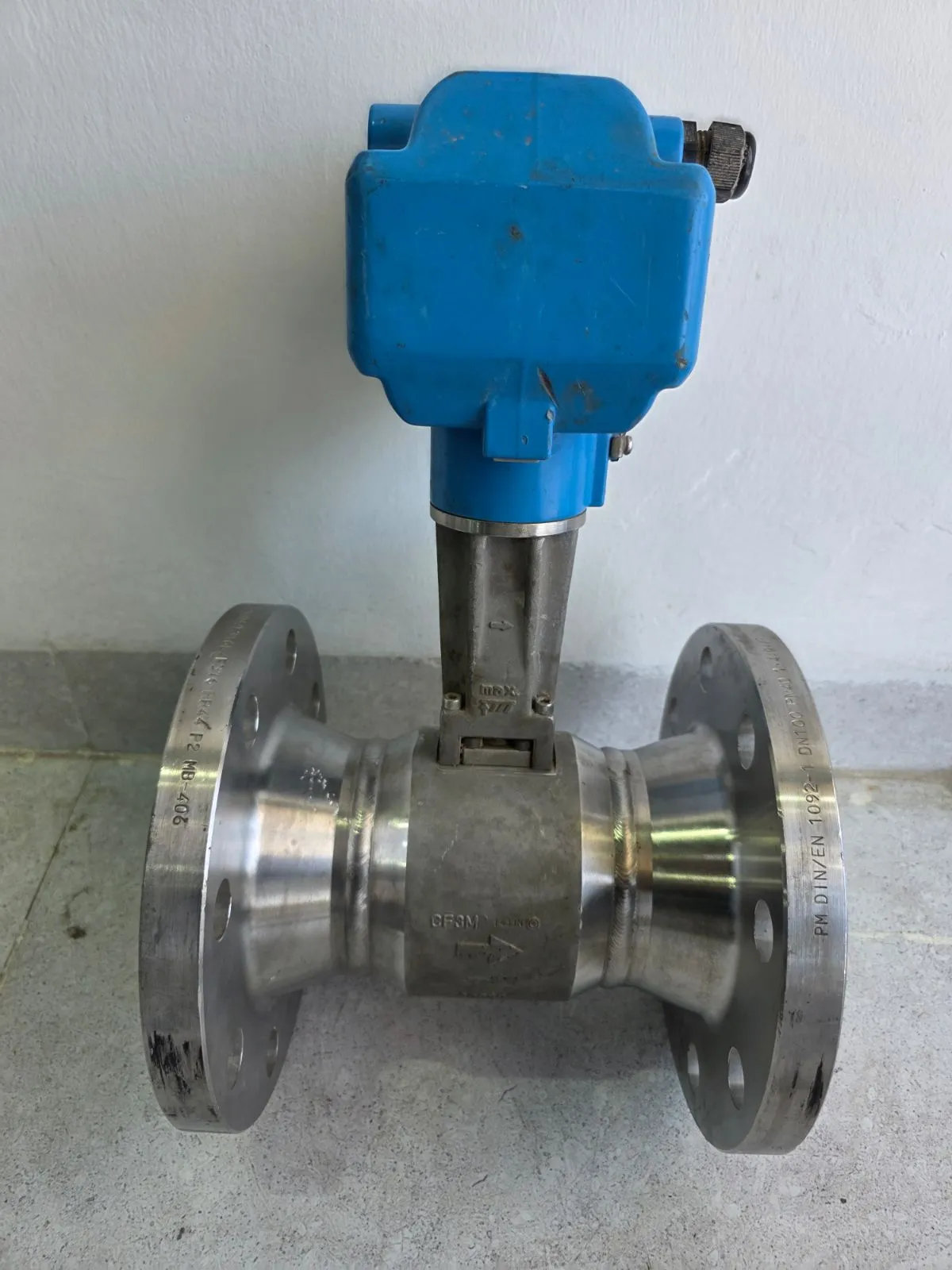 Side view with blue transmitter head and CF3M stainless body showing flow-direction arrow and DSC sensor paddle