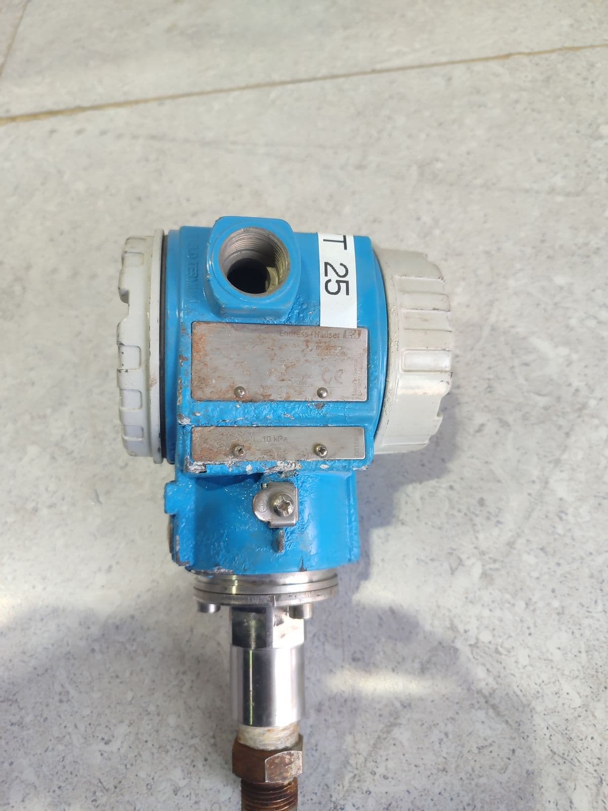 Pressure transmitter with both nameplates wiped blank — model unidentified — warehouse tag sticker «T 25» — this device's own nameplates are wiped blank, in Barmaan's warehouse